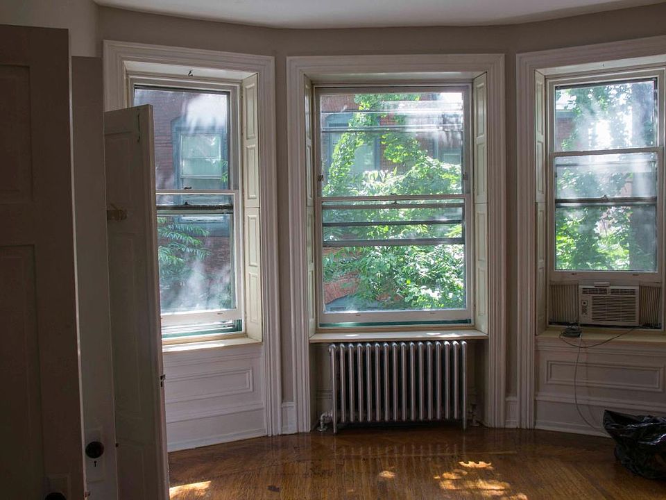 Living room has bay window that looks out on a garden.