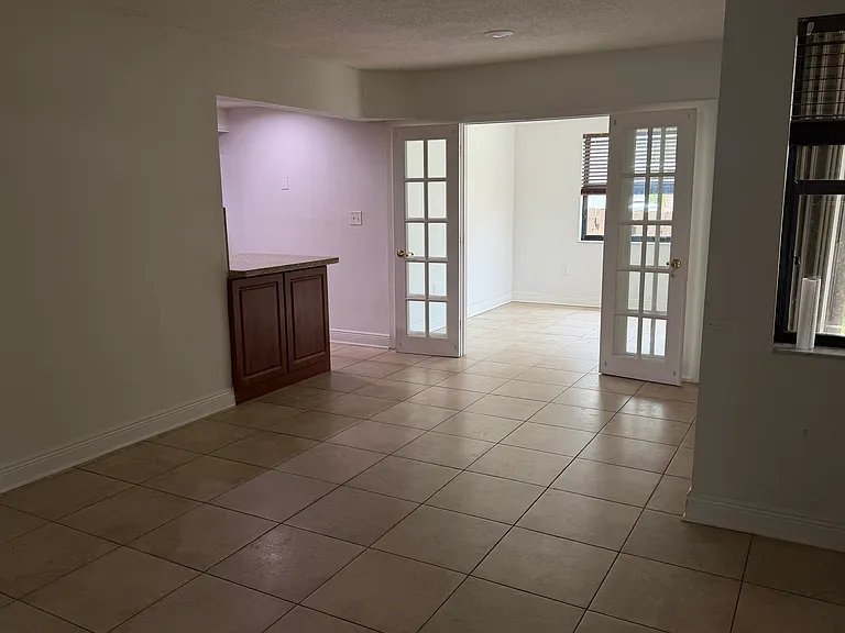 View of kitchen and side sun room with glass door that leads to patio.