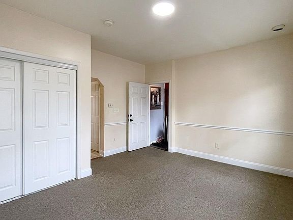 View of living room. Shown is the closet in the living room, main entrance and the arched entrance to the kitchen.