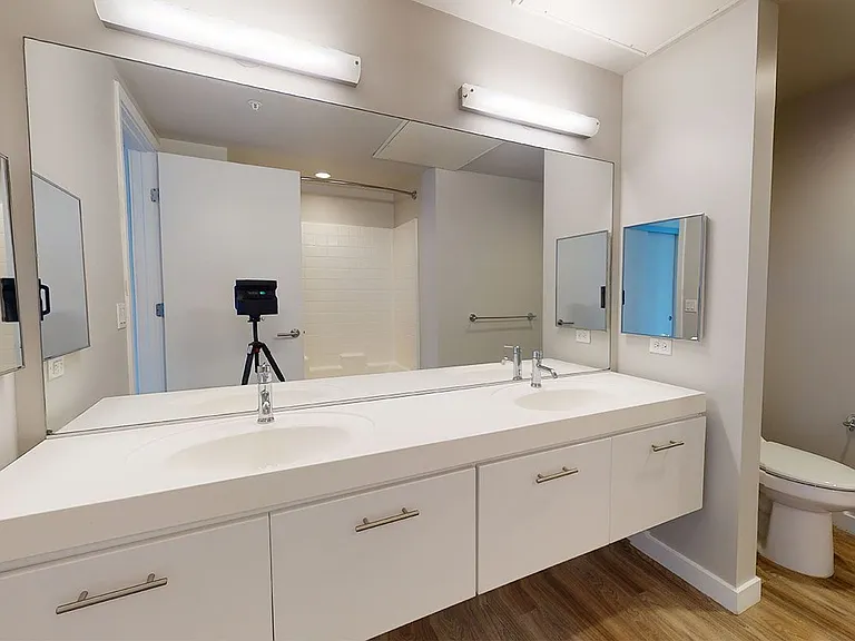 Apartment bathroom with wood-style flooring and double sinks.