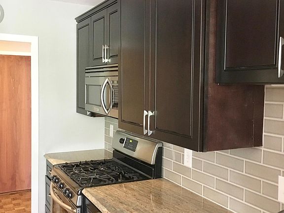 Kitchen with granite counters, espresso cabinets, stainless steel appliance, and soft gray crackle subway backsplash.