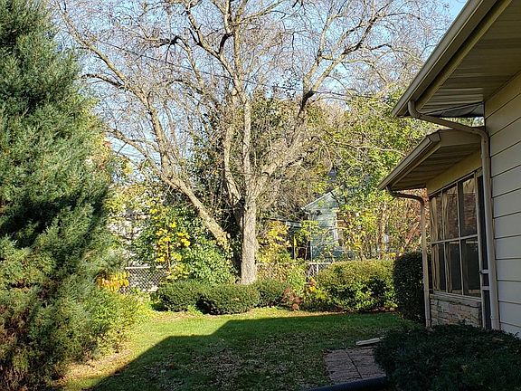view of backyard with three-season porch. New gutters with gutter-guards have been installed to improve drainage and waterflow.
