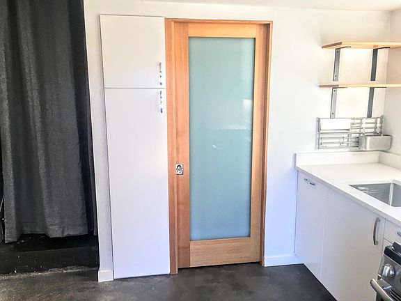 Tall built-in pantry with roll-out drawers provides a lot of storage. Opaque glass on pocket door to bathroom allows for privacy while letting all the light in.