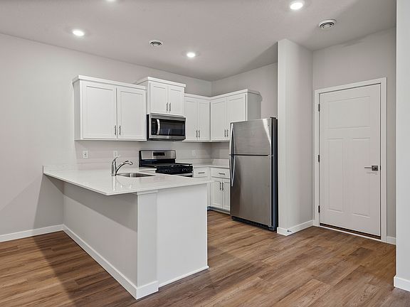 The kitchen has stainless steel appliances and plank flooring