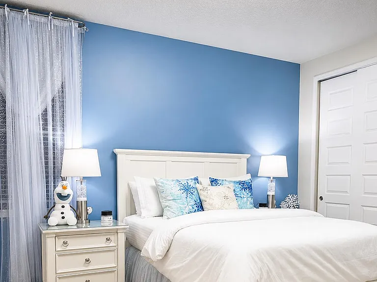 Well-appointed bedroom with a full/queen bed, dual nightstands, and a closet, plus a window with sheer drapes.