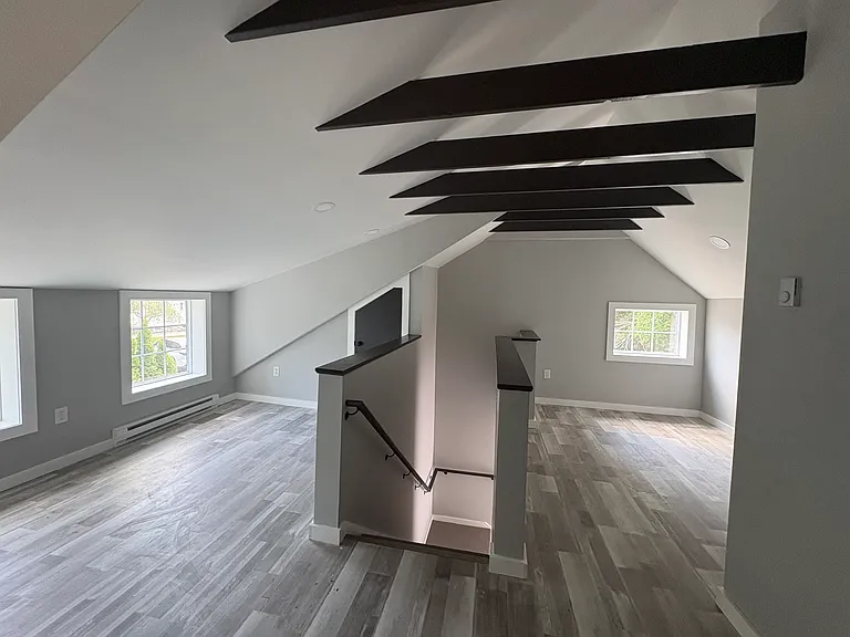 Full loft view with exposed beams and windows on all sides