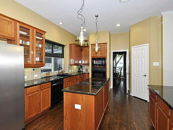 Island kitchen boasts granite surfaces & rich wood cabinets