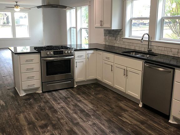 Beautiful kitchen with gas range and ceiling mounted stainless steel range hood and dishwasher