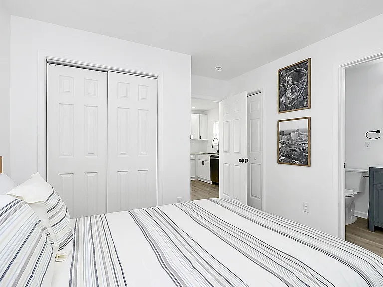 Bedroom with a large queen bed, side table and closet.