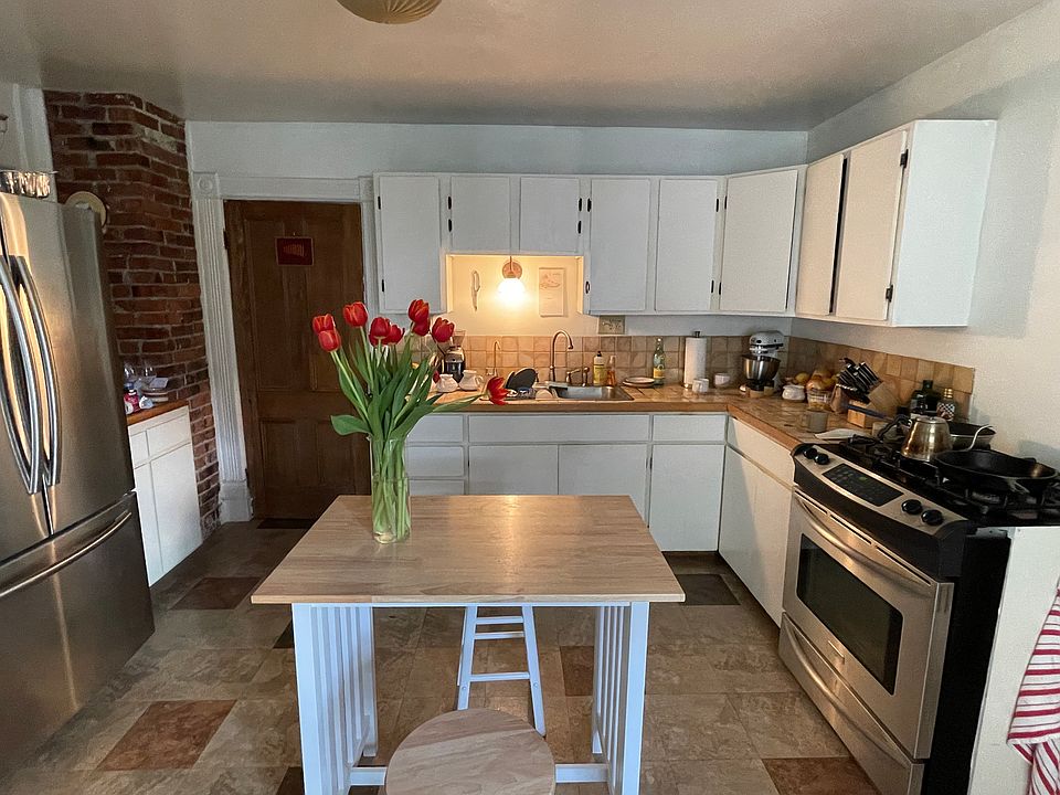 Kitchen is now white with granite countertops and wood floors.