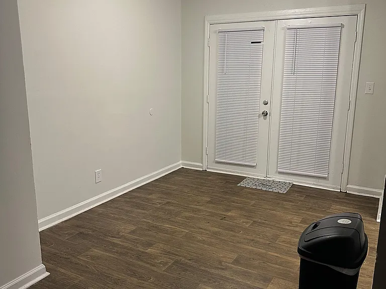 Flexible open living area with durable wood-look flooring and French doors offering easy access to the outdoors.