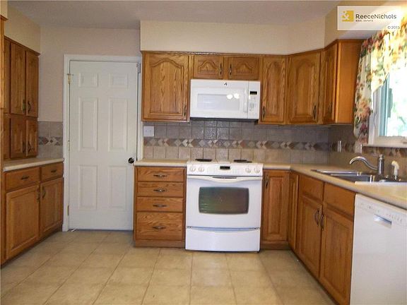 Kitchen with newer Back Splash, Electric Range, Micro-Wave, and Dishwasher. Door goes to oversized 2 car Garage.