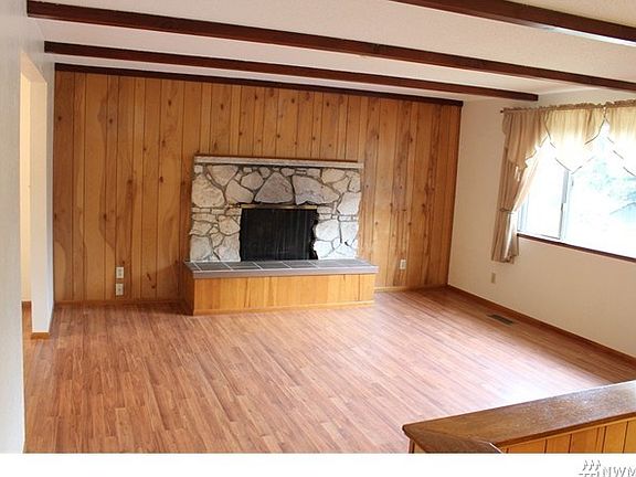 Living room with newer laminate flooring, wood burning fireplace and easy access to dining and kitchen areas.