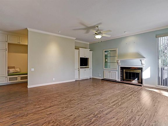 The spacious and light-filled living room has built-in cabinets, a cozy fireplace and floor to ceiling windows.