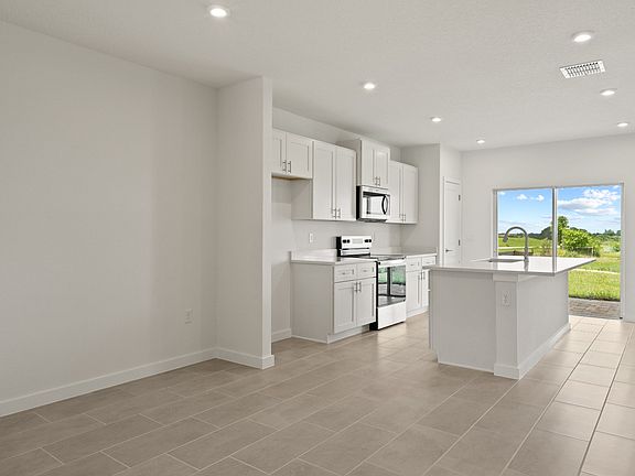 Bright kitchen with shaker-style cabinetry, large island, and natural light pouring in through slidi