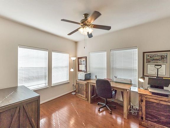 The study has gleaming wood floors and a ceiling fan.