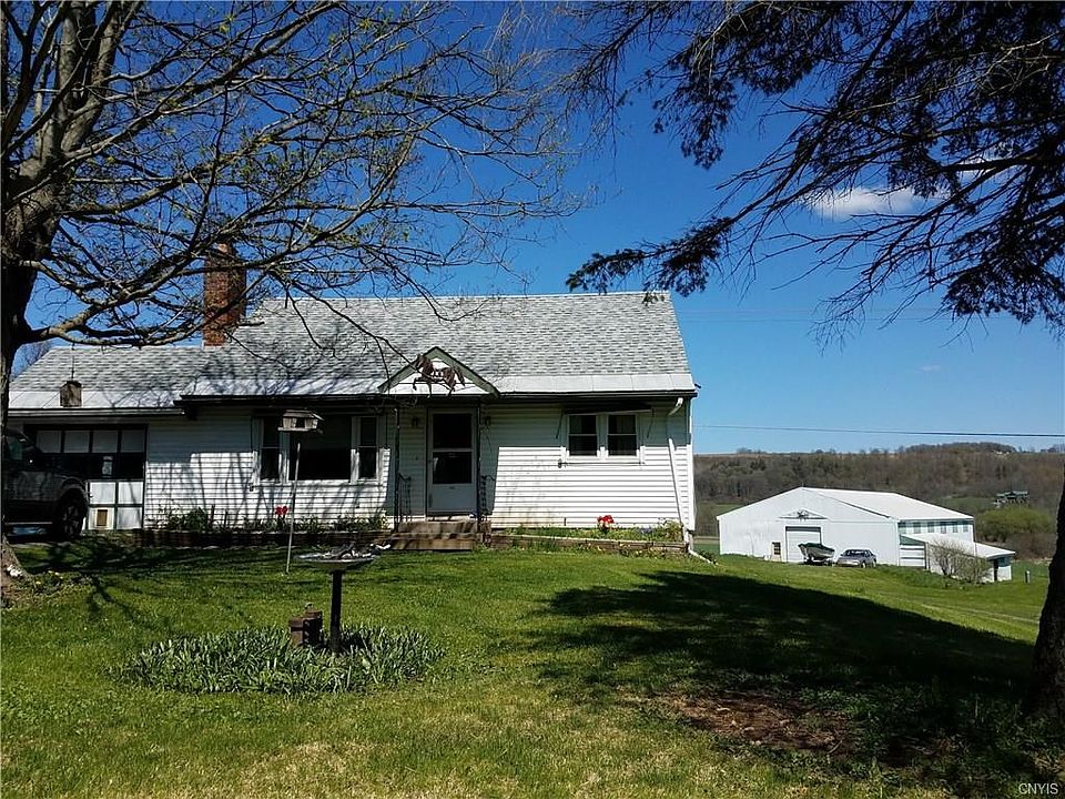 Front of house with attached garage to left(out of frame) and large area in background.