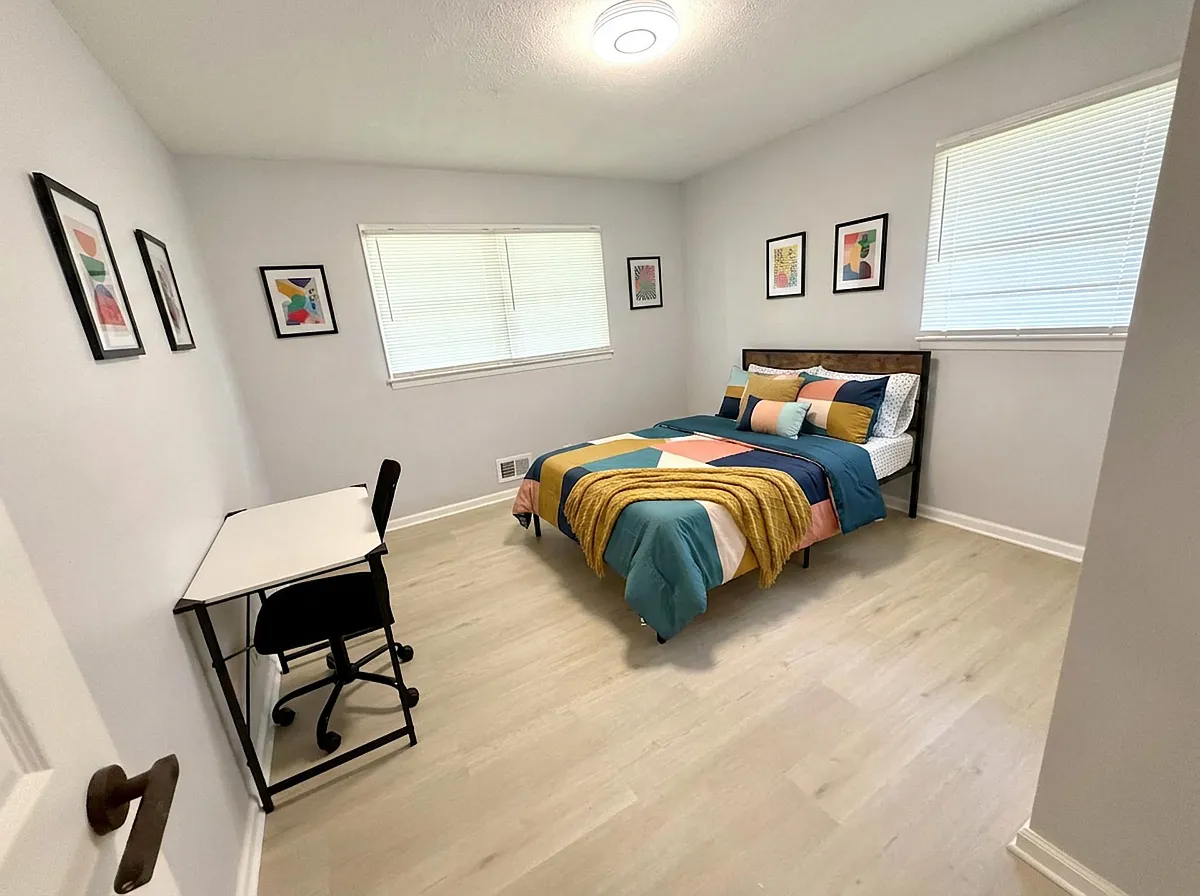 Photo 2 of 3 - Dogwood Dr NW - Lawrenceville, GA Spacious bedroom with a full bed, desk workspace, and dual windows with blinds for adjustable light and privacy. - Dogwood Dr NW