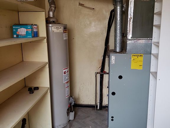 Large utility room is behind the kitchen sink, has storage shelves, washer, dryer hook-up, furnace and hot water heater.