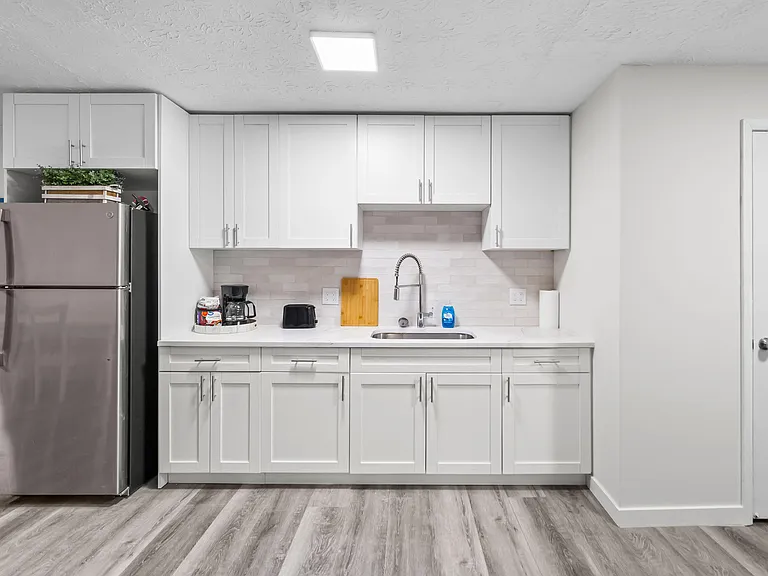 Streamlined kitchen with generous cabinet storage, full-size refrigerator, and wide counters anchored by a stainless sink.