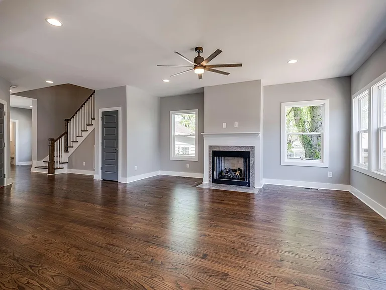 View of living room - garage door can be seen on the left and large storage closet door on the right. You can also see the entry way and half bathroom beyond the stairs.