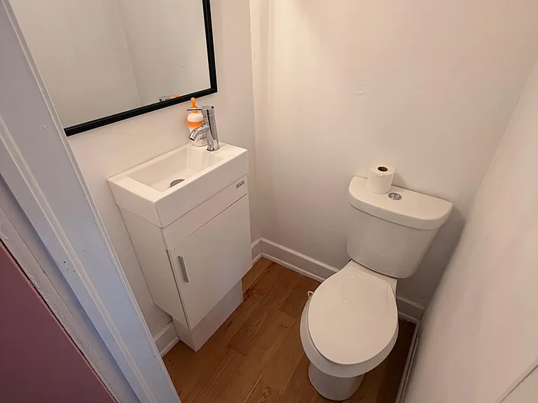 Compact half bath featuring a modern vanity with storage, framed mirror, and easy-care wood-look flooring.