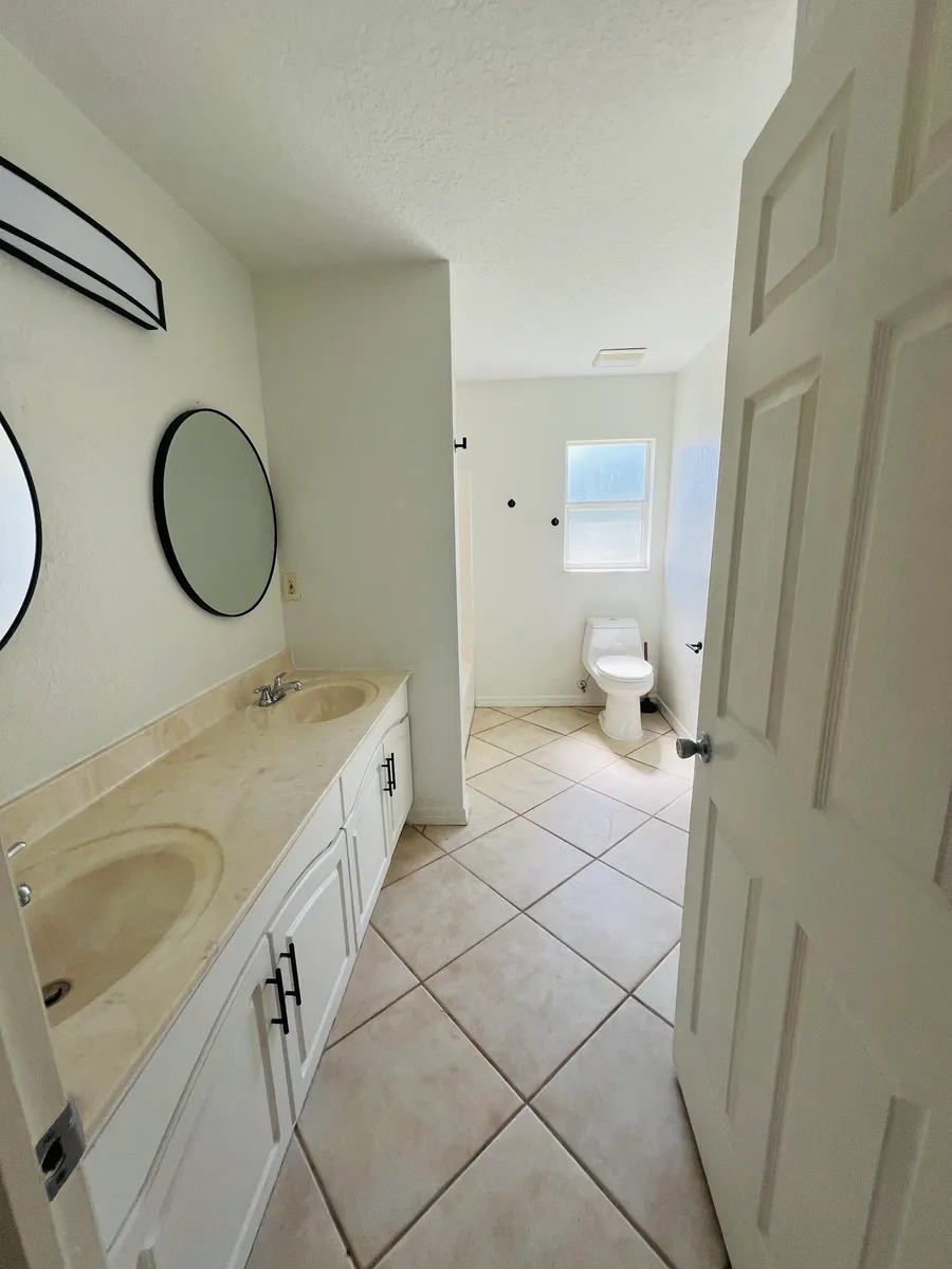 Hallway bathroom with double vanity sinks. - 7910 Rose Ave