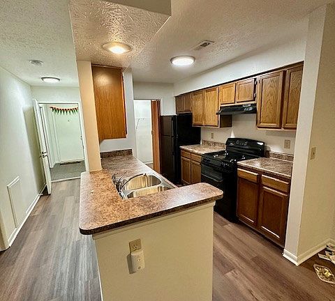 The kitchen has new counters, a new black stove and a black dishwasher, and a refrigerator