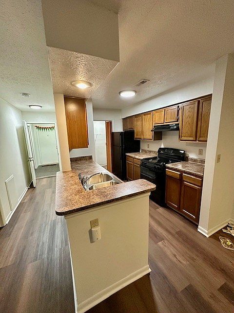 The kitchen has new counters, a new black stove and a black dishwasher, and a refrigerator