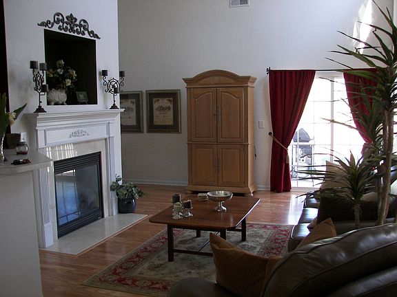 Bright two-story living room with hardwood floors and marble fireplace