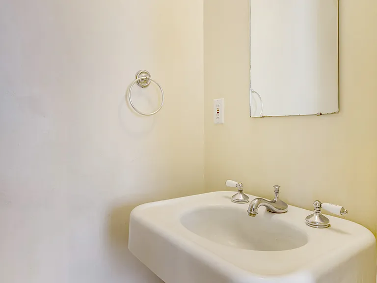 Bath includes a pedestal sink, original flooring, and a toilet.