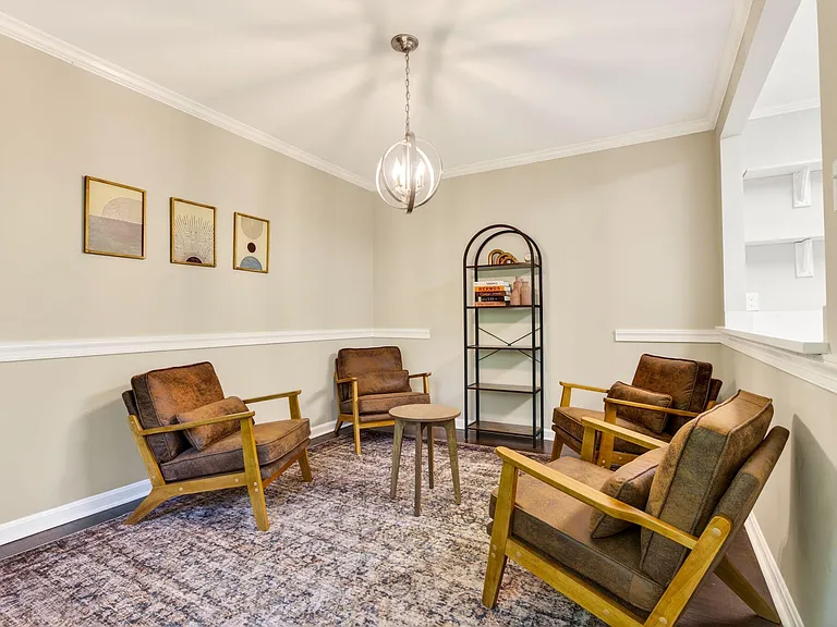 Common lounge with four accent chairs, area rug, side table, and shelvingideal for relaxing or small group chats.