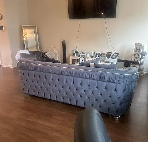 Spacious living area with wood-look floors, a tufted sectional, and wall-mounted TVideal for relaxing or entertaining.