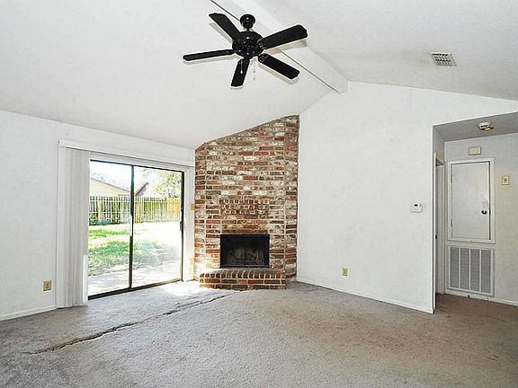 Fireplace and ceiling fans are featured in the open family room with a view of the patio and back yard.