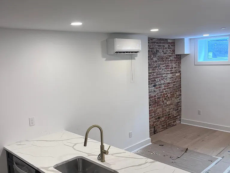 Open living area with exposed brick accent features. High ceilings and original exposed brick accents meet modern open-concept layouts *This is a layout from apartment 1, each apartment features unique living area layouts*