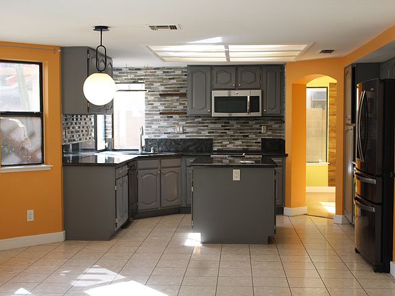 Kitchen with Tile walls, hanging pan rack over sink, big island