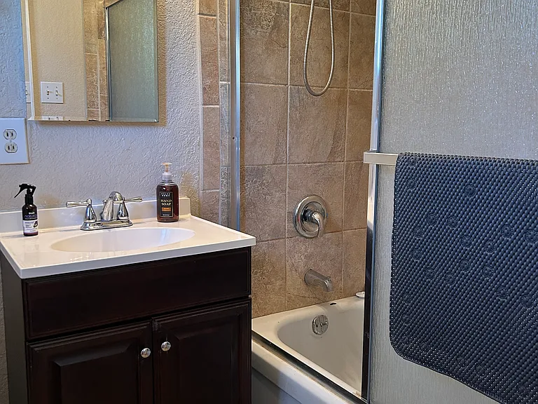 Private ensuite bathroom with glass doors on shower/tub combination and adjustable dial shower head.