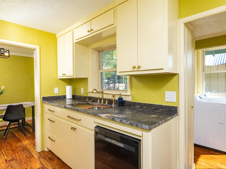 Bright, fully equipped kitchen with stainless steel appliances, warm wood floors, and modern yellow cabinets_perfect for cooking and relaxing at home.