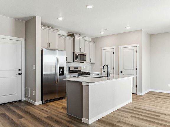 The kitchen has stainless steel appliances and plank flooring.
