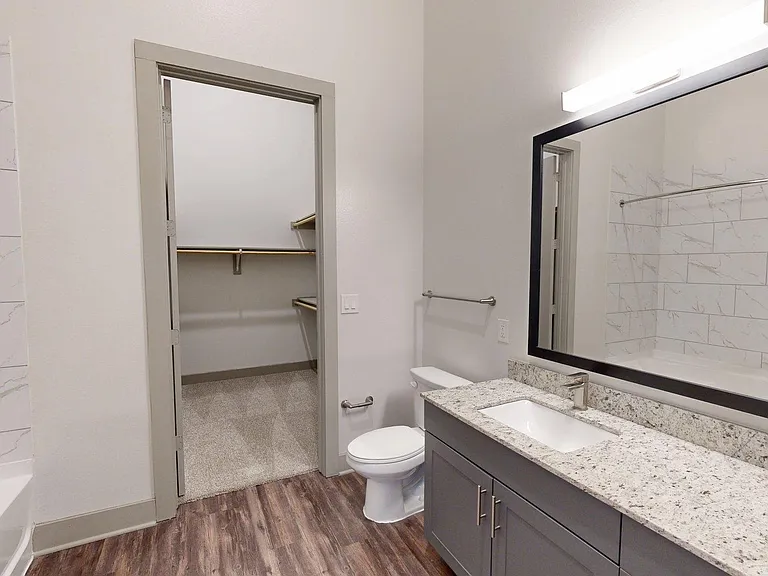 Apartment Bathroom with LED vanity mirror and Wood Style Flooring.