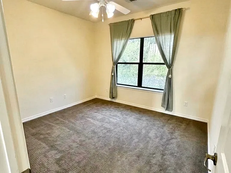 Cozy guest bedroom with ceiling fan, carpet, and big window overlooking greenery from the private backyard bringing in lots of natural light