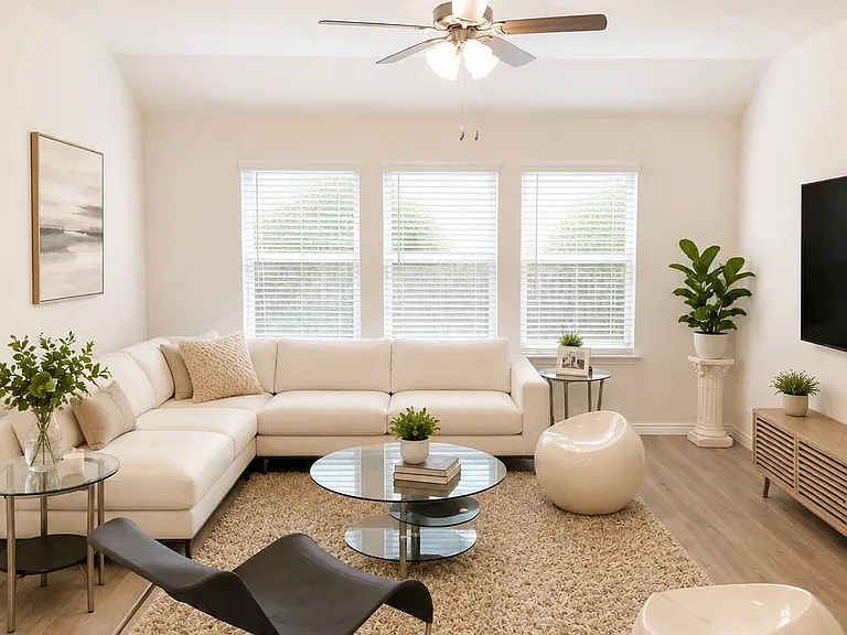 Vaulted ceiling living area featuring a ceiling fan with light kit, three large windows with blinds, and wood-finish flooring