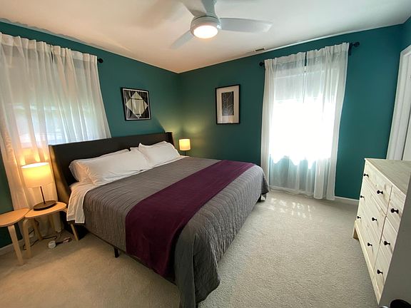 The back bedroom features a king bed and six-drawer dresser. It opens into the half-bath.