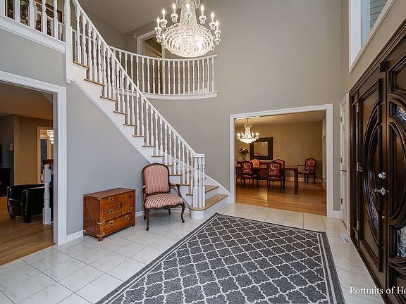 Grand Foyer w/. Curved Staircase, Exquisite Crystal Chandelier & 18 ft. Ceiling.