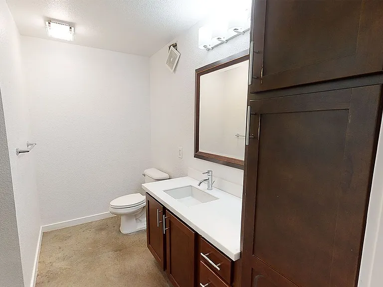 Apartment bathroom with polished concrete flooring.
