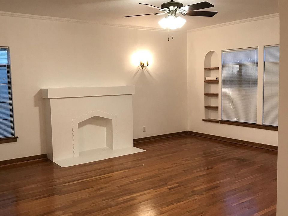 Large living room with Solid Oak Floors antique wall sconces, fan light and original wooden book shelves.