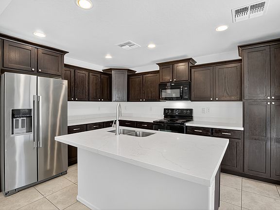 Modern kitchen with stainless and black appliances and dark wood cabinetry.