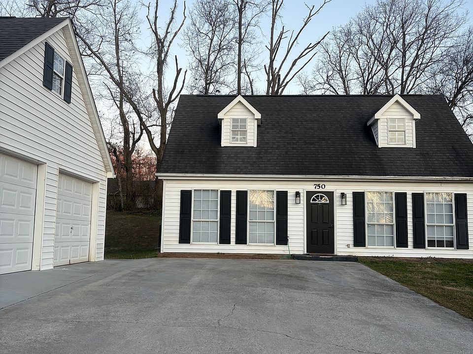 front of house with a detached 2 car garage with large parking pad driveway