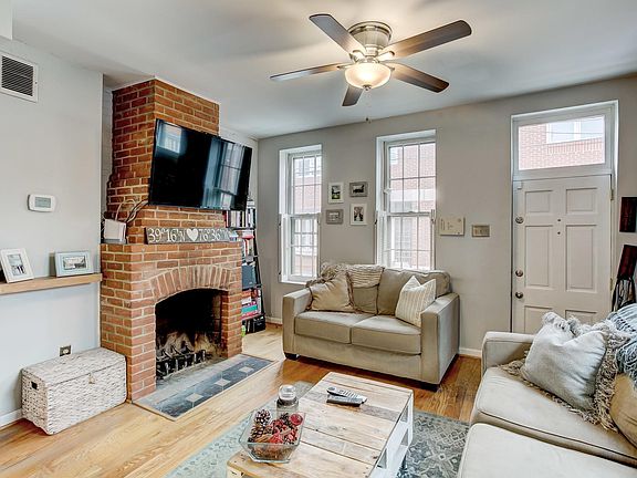 Living room features hardwood floors, wood burning fireplace, and exposed brick.