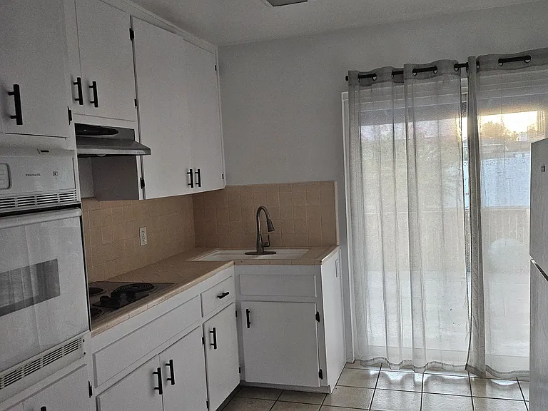 Kitchen with over, stove, sink and fridge.